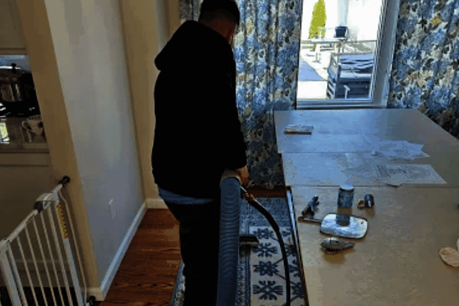 Technician cleaning a blue and white runner rug next to a dining table