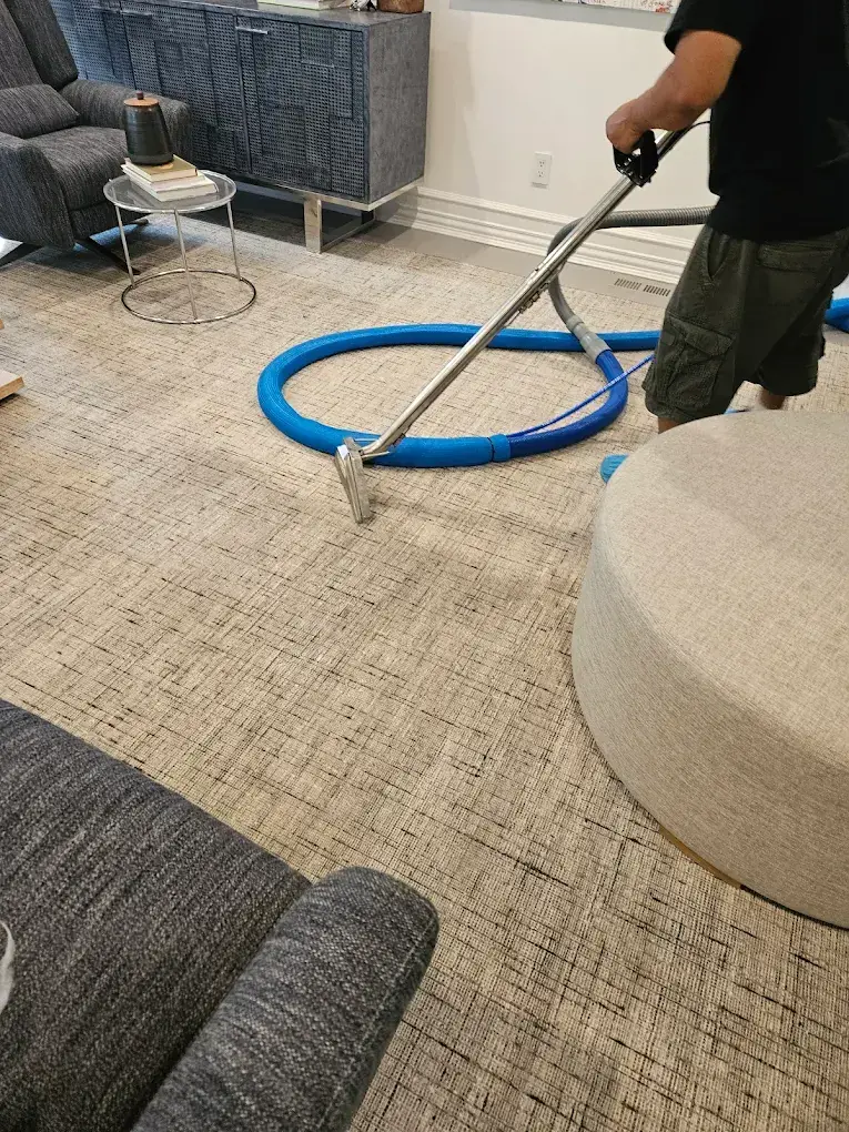 Technician cleaning a large woven area rug with a wand and hose